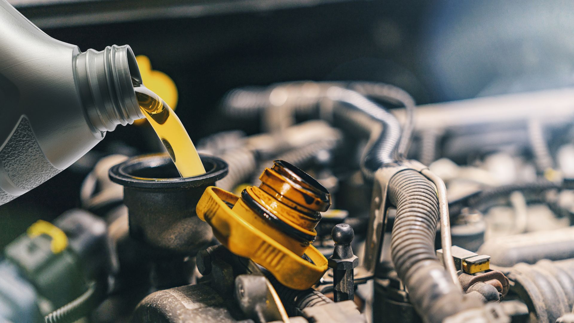 A close up of a car engine with oil being poured on it