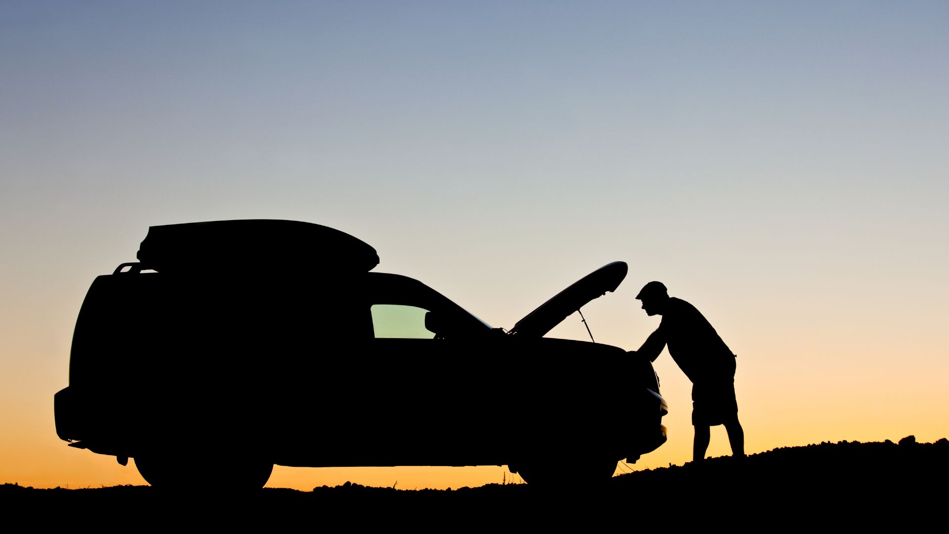 A man standing next to a car with a surfboard on top of it